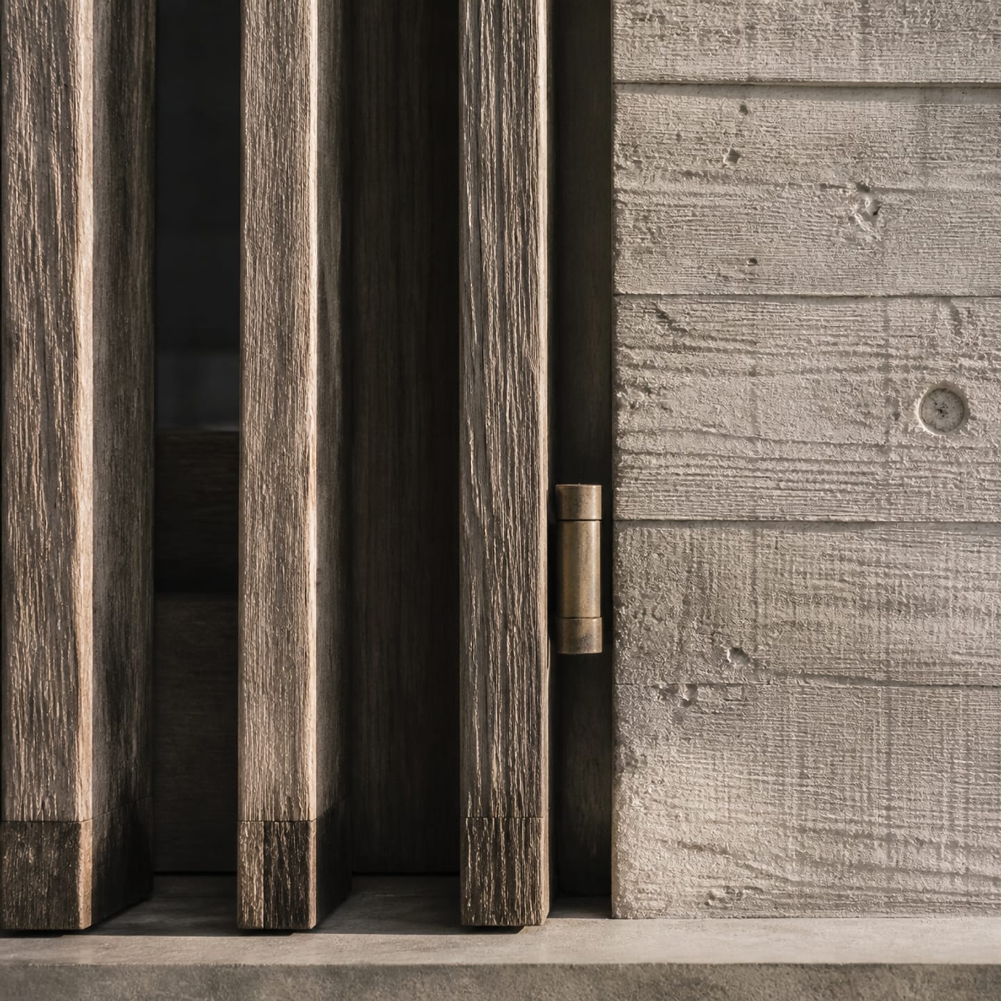Close view of weathered ironwood screens meeting a mineral concrete wall