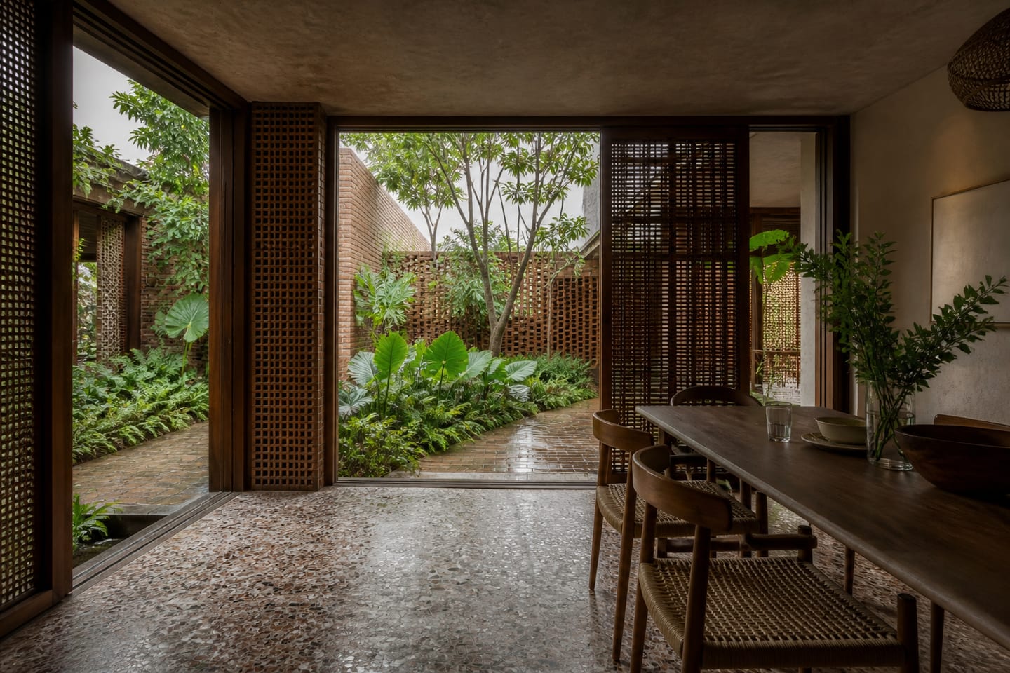 Family dining space opening completely to a terracotta and tropical garden courtyard